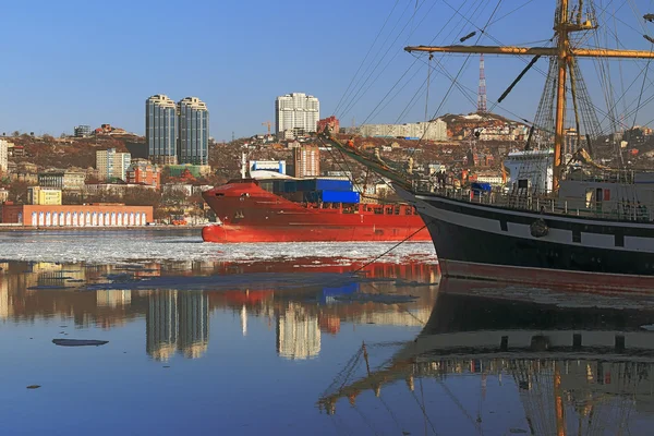 Reflection sailing ship and buildings of the city of Vladivostok in winter sea surface — Φωτογραφία Αρχείου