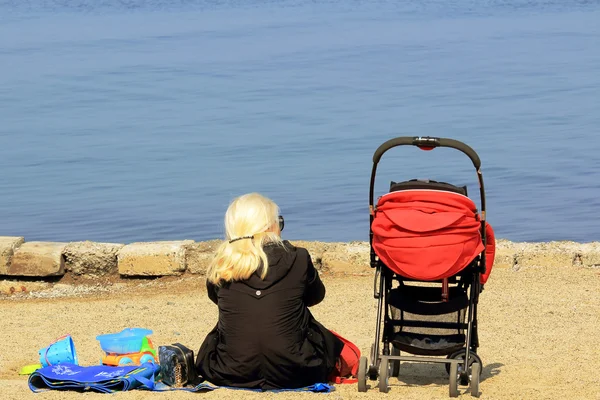 Denize bakarak çocuk arabası olan bir kadın