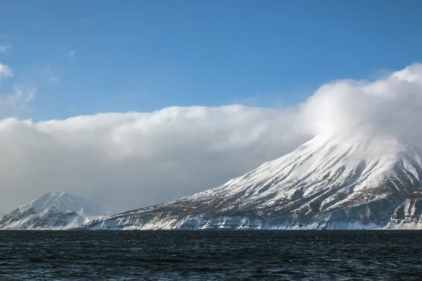 Snowy vulkan på havet og blå himmel baggrund - Stock-foto