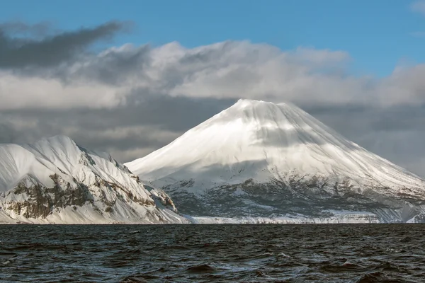 Χιονισμένο ηφαίστειο για την θάλασσα και το γαλάζιο φόντο του ουρανού — Φωτογραφία Αρχείου