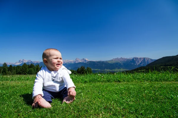 Roztomilé dítě sedí na zelené trávě s Dolomiti panorama na zádech — Stock fotografie
