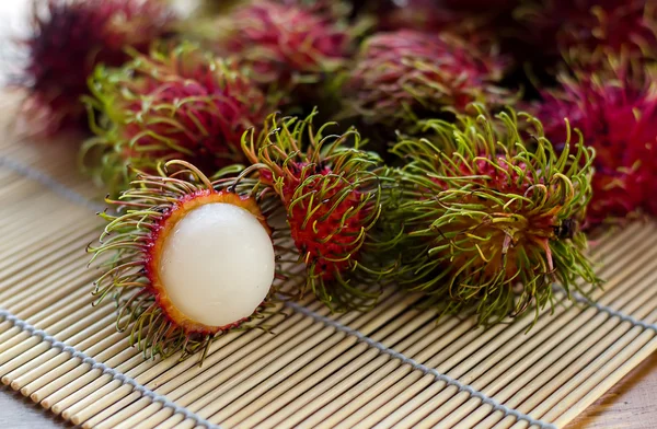 Röda rambutans på träbord — Stockfoto