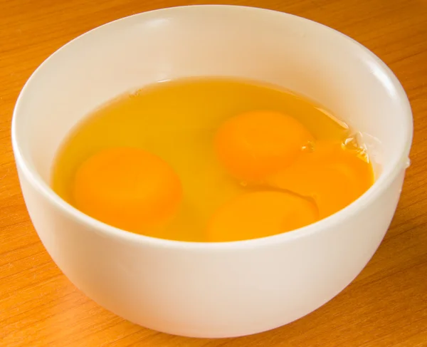 Разбивает яйцо в чашке — стоковое фото