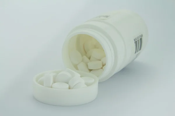 bir ilaç şişesi beyaz zemin üzerine beyaz hap
