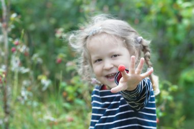 İki yaşında sarışın kız kırmızı Bahçe ahududu meyve paylaşımı gülüyor