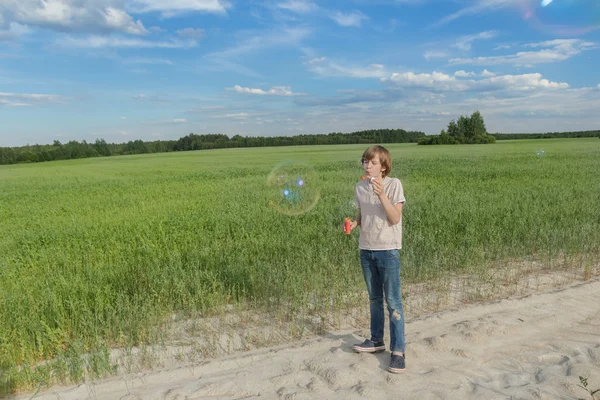 Ragazzo adolescente che fa bolle di sapone sulla strada polverosa campo terra fattoria — Foto Stock