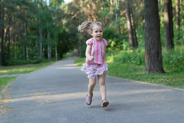 Rubia chica de tres años corriendo en el sendero del parque de asfalto —  Fotos de Stock