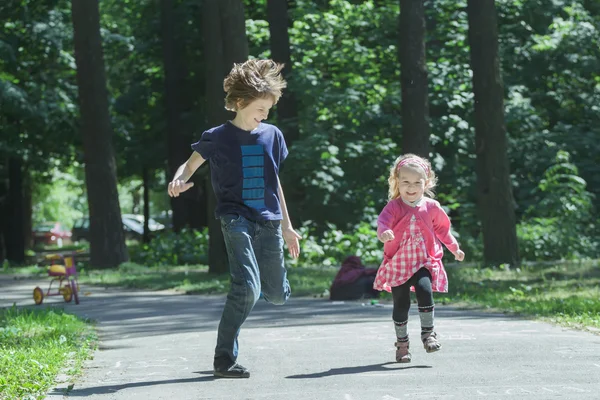 Rire enfants frères et sœurs jeu tag et courir sur le sentier de l'asphalte parc — Photo