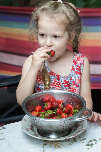 Retrato de una niña comiendo frutas rojas dulces de fresa de cullender —  Fotos de Stock