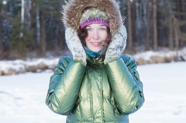 Kafasını yakınındaki yünlü eldivenler Turnuvası'na kış orman içinde açık havada tutan mutlu genç kadın