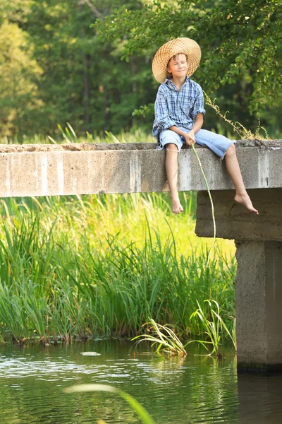 Jongen tijdens visserij met staaf op de brug — Stockfoto