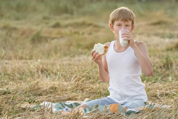 Teenage farmer boy smak färsk mjölk och bröd — Stockfoto