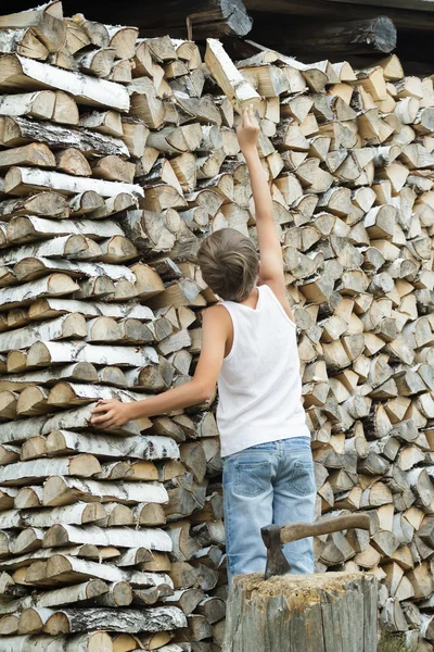 Подросток раскладывает дрова в стопку — стоковое фото