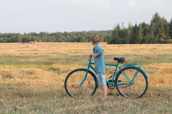 Teenager boy holding bicycle in farm field — Stock Photo, Image