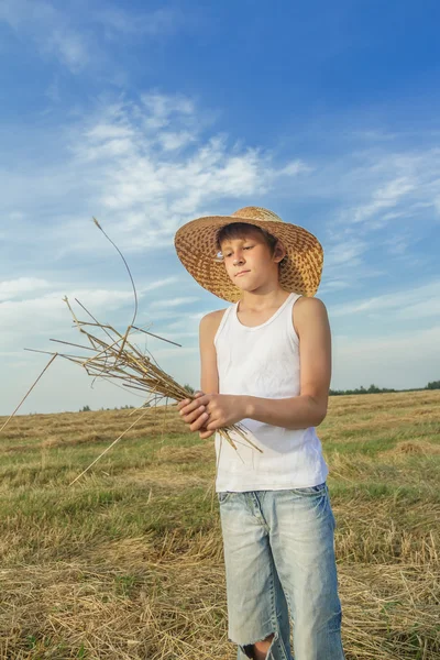 Молодой фермер держит связку соломы — стоковое фото