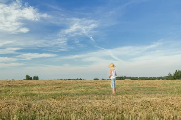 Agricultor adolescente em pé no campo colhido — Fotografia de Stock