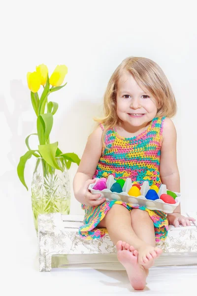 Little girl with Easter colored eggs in arms — Stock Photo, Image