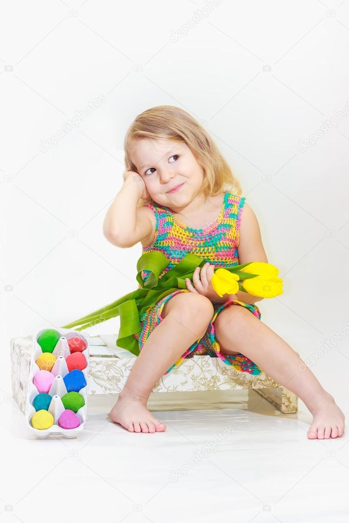 Little girl is holding tulips with Easter eggs