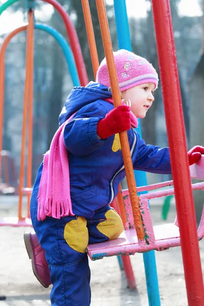 Zweijähriges Mädchen sitzt auf Spielplatz-Schaukel — Stockfoto