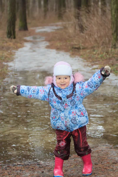 Двухлетняя девочка исследует ледяную лужу — стоковое фото