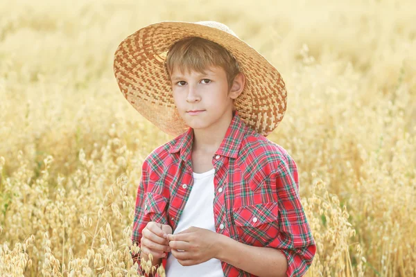 Kırmızı kareli gömlek ve sarı geniş ekledi doğal hasır şapka giyen genç çiftçi çocuk portresi Stok Resim