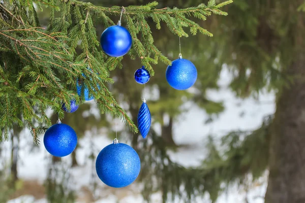 Outdoor Christmas azure shiny bauble ornaments hanging on snowy spruce twig — Stock Photo, Image