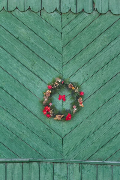 Festlicher Weihnachtskranz hängt an alter rustikaler grüner Tür — Stockfoto