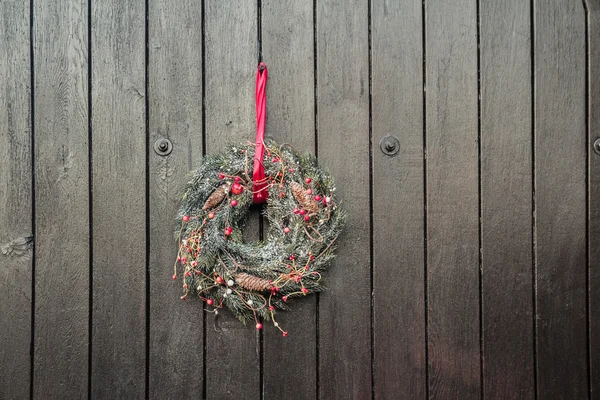 Christmas Holiday Advent wreath hanging outside at brown wooden gates background