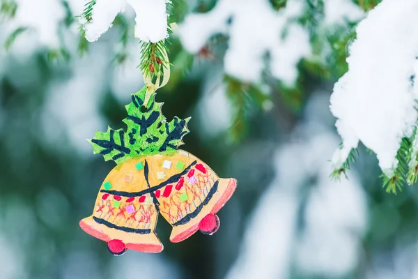 Деревянный орнамент рождественских колоколов, висящих на снежной елке Стоковое Фото