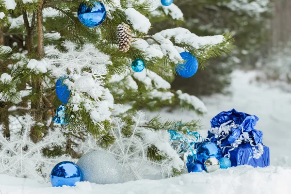 Evergreen karlı çam ağacı Noel baubles ile dekore edilmiş ve hediyeler yere sarılmış