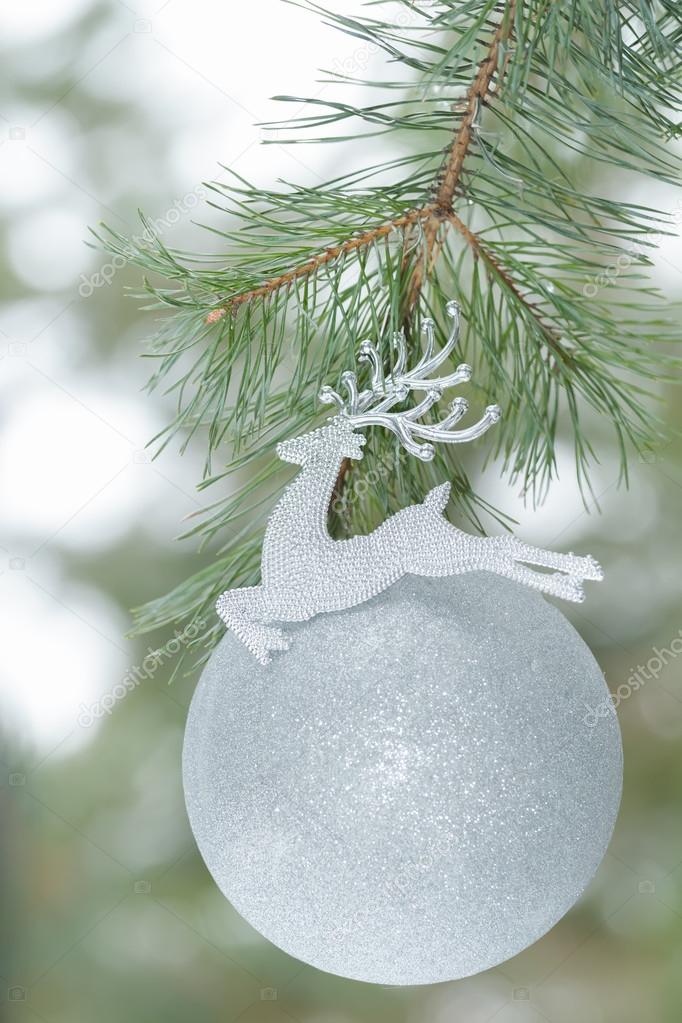 Polished silver color Christmas ornament as Santa Claus reindeer on pine branch