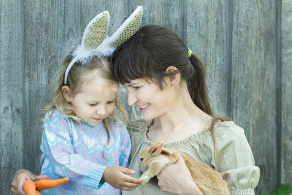 Madre y su hijo sosteniendo lindo conejo de Pascua escarlata — Foto de Stock