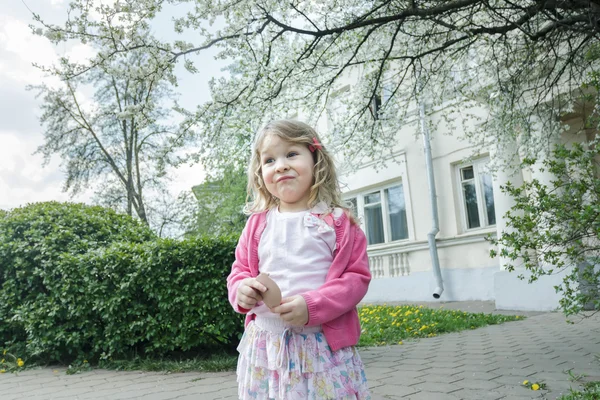 Retrato divertido al aire libre de niña mueca en el jardín de árboles frutales en flor con espejo de bolsillo en la mano —  Fotos de Stock