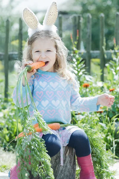 Preschooler blonde girl wearing Easter rabbit costume gnawing fresh carrot — Stock Photo, Image