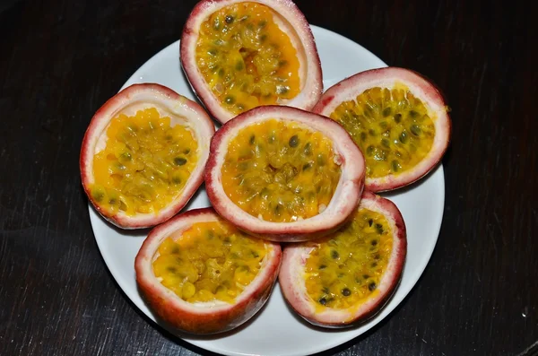 Halved passion fruit lying on the white plate — Stock Photo, Image