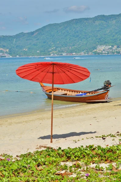 Parasol rouge sur la plage contre la mer et les bateaux — Photo