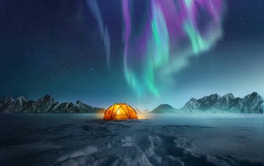 A tent pitched up in snow at night with the northern lights flickering in the sky above. Aurora Borealis and travelling. Photo composite. clipart
