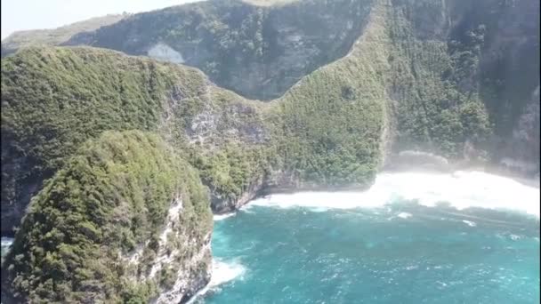 Kelingking Beach, Nusa Penida, Μπαλί, Ινδονησία. Αεροφωτογραφία αυτού του όμορφου θαλασσινού τοπίου με τα γαλαζοπράσινα νερά, τα κύματα που συντρίβονται και το πράσινο. — Αρχείο Βίντεο