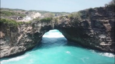 Okyanus suyunun gücüyle yaratılmış doğal bir köprü. Endonezya 'nın Nusa Penida adasındaki Kırık Plaj' ın ünlü turistik yerinin hava görüntüsü.
