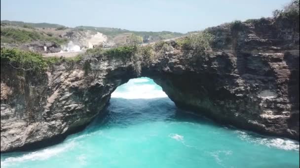 Un puente natural creado por la fuerza del agua del océano. Foto aérea del famoso lugar turístico de Broken Beach en la isla de Nusa Penida, Indonesia — Vídeo de stock