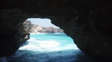 Kaya kıyı şeridi ve taş kemer Endonezya 'da, Nusa Penida' daki gök mavisi deniz üzerinde. Hava görüntüsü 4K