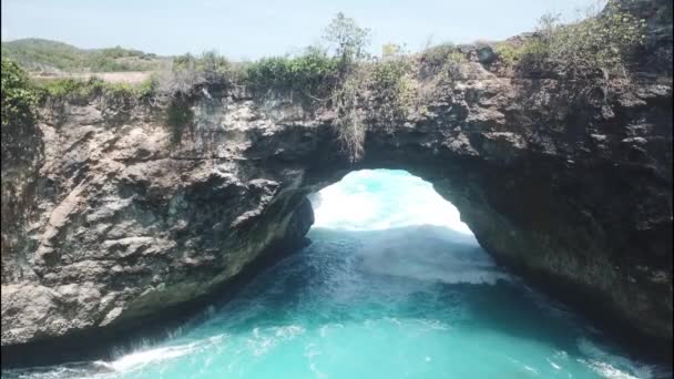 Drone footage of the west coast of Nusa Penida, Indonesia near Angel Billabong and broken beach with its rocky shore scattered with few bushes, big waves are crashing into the rocks — Stock Video
