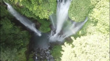 Tropikal Asya şelalesinin aşağı manzarası. Yeşil yağmur ormanlarında şelale. Dağ ormanındaki üçlü şelale manzarası. Bali, Endonezya. Seyahat konsepti. Hava görüntüleri