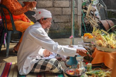 Bir düğün töreninde dua eden Hindu rahibi. Pedanda adakların önünde oturur ve nikah kıyar.