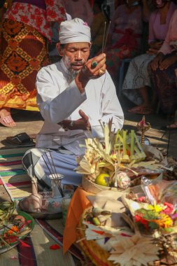 Tören sırasında Hindu rahiplerin önünde. Pedanda kurbanların önünde oturur ve düğün törenlerini düzenler..
