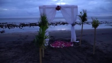 Tropikal sahilde egzotik düğün Avrupa tarzı kemer. Siyah kumsalda düğün kapısı. Romantik sabah şafağı. 4K video
