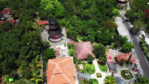 Vista aérea de la torre del templo naranja en una colina verde, monasterio budista Brahma Vihara Arama, avanzando — Vídeo de stock