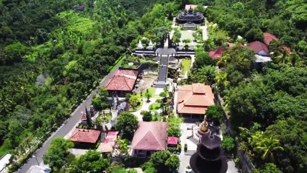Vista aérea de la torre del templo naranja en una colina verde, monasterio budista Brahma Vihara Arama, avanzando — Vídeo de stock