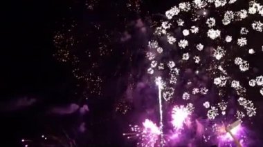 Parlak havai fişek gösterisi. Kara gece gökyüzünde parçacıkların ve kıvılcımların olduğu havai fişekler. Gerçek havai fişek sahnesi. Bokeh 'le parlayan havai fişekler. Yeni yıl arifesi havai fişek kutlaması.