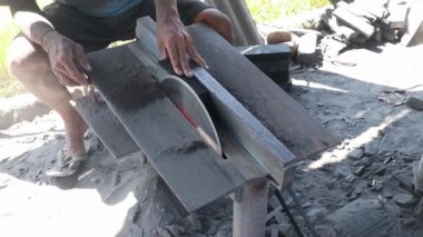İnsan siyah taşı kesmek için taş kesiciyi kullanır.